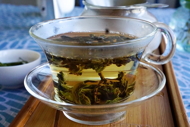 Valokuva läpinäkyvässä gaiwanissa hautuvista valkoisen teen lehdistä