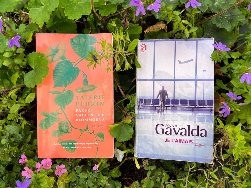 Kaksi kirjaa aseteletuna kukkaistutuksen keskellä.