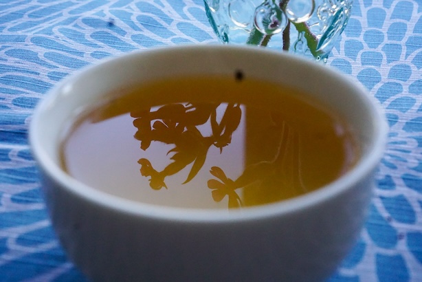 Valokuva teekupista, jossa heijastuu kukkakimppu