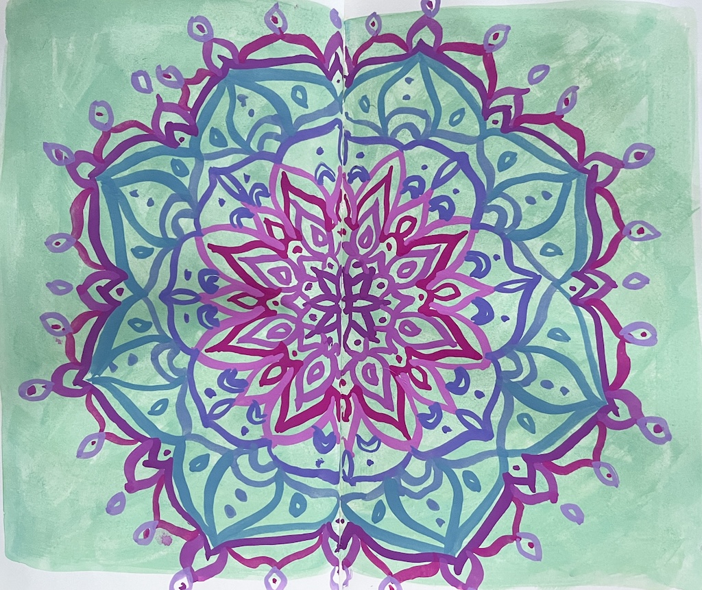 Turkoosille taustalle maalattu monivärinen mandala