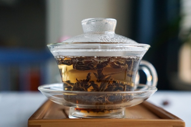 Kuva punaisen teen lehdistä, jotka hautuvat lasiessa gaiwanissa