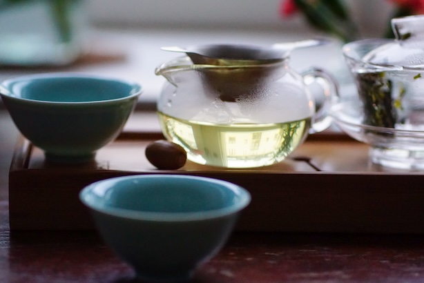 Teemaistelutarvikkeita ja lasinen teekannu, jossa vihreää teetä