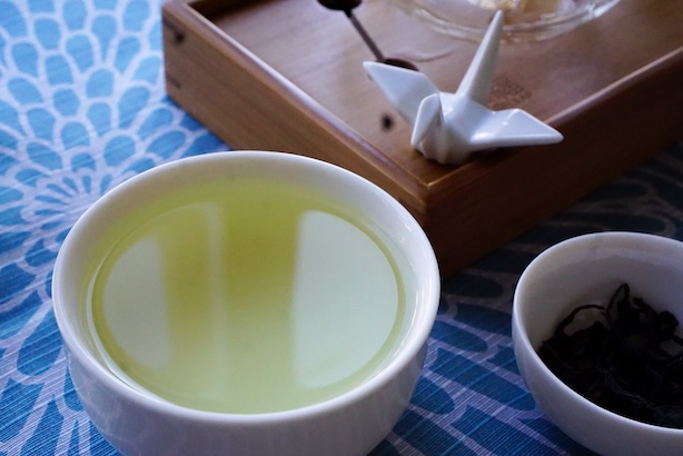 Valokuva teekupista, jossa on vihreää teetä ja maskottikurjesta