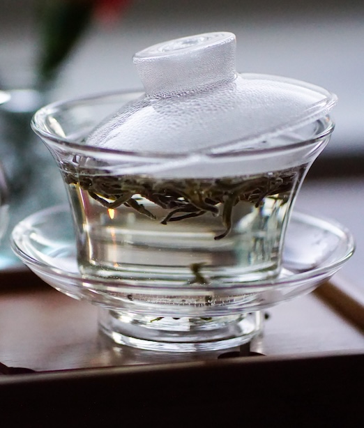 Lasinen gaiwan, jossa valkoista teetä hautumassa