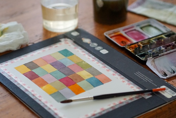 Valokuva värimeditaatioruudukosta ja maalaustarvikkeista