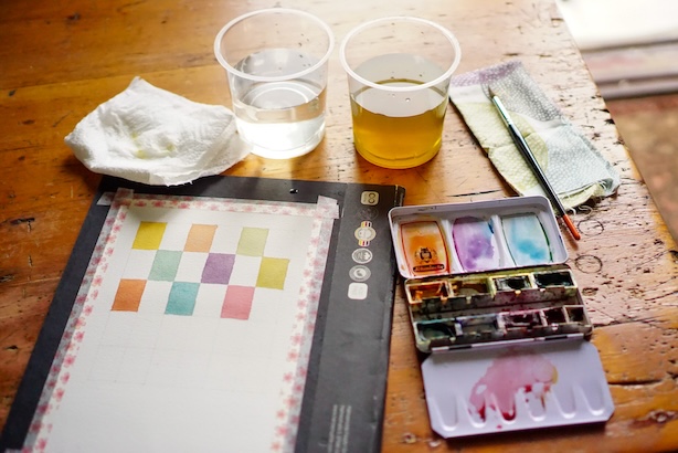 Valokuva värimeditaatioruudukosta ja maalaustarvikkeista