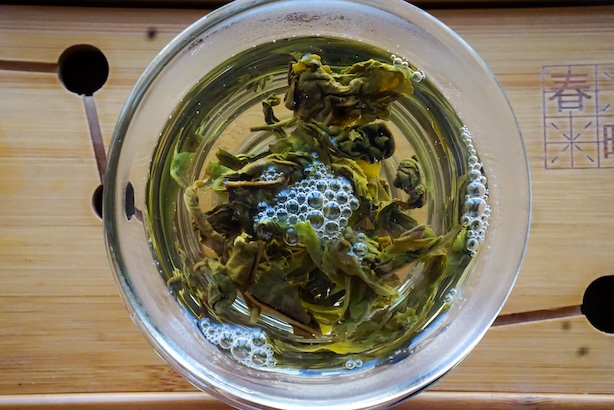 Valokuva gaiwanin yläpuolelta, missä teenlehdet aukeavat kuumassa vedessä